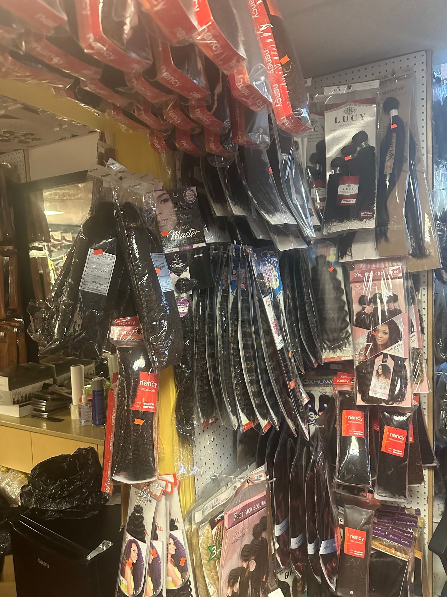 Hair extensions and wigs displayed in various packages on a store shelf.